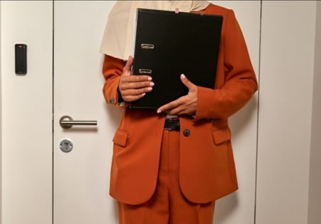 unrecognizable woman in a suite holding paperwork