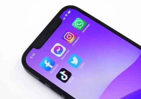 black iphone with purple background showing social media icons
