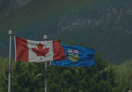 canadian flag and alberta flag in front of mountains